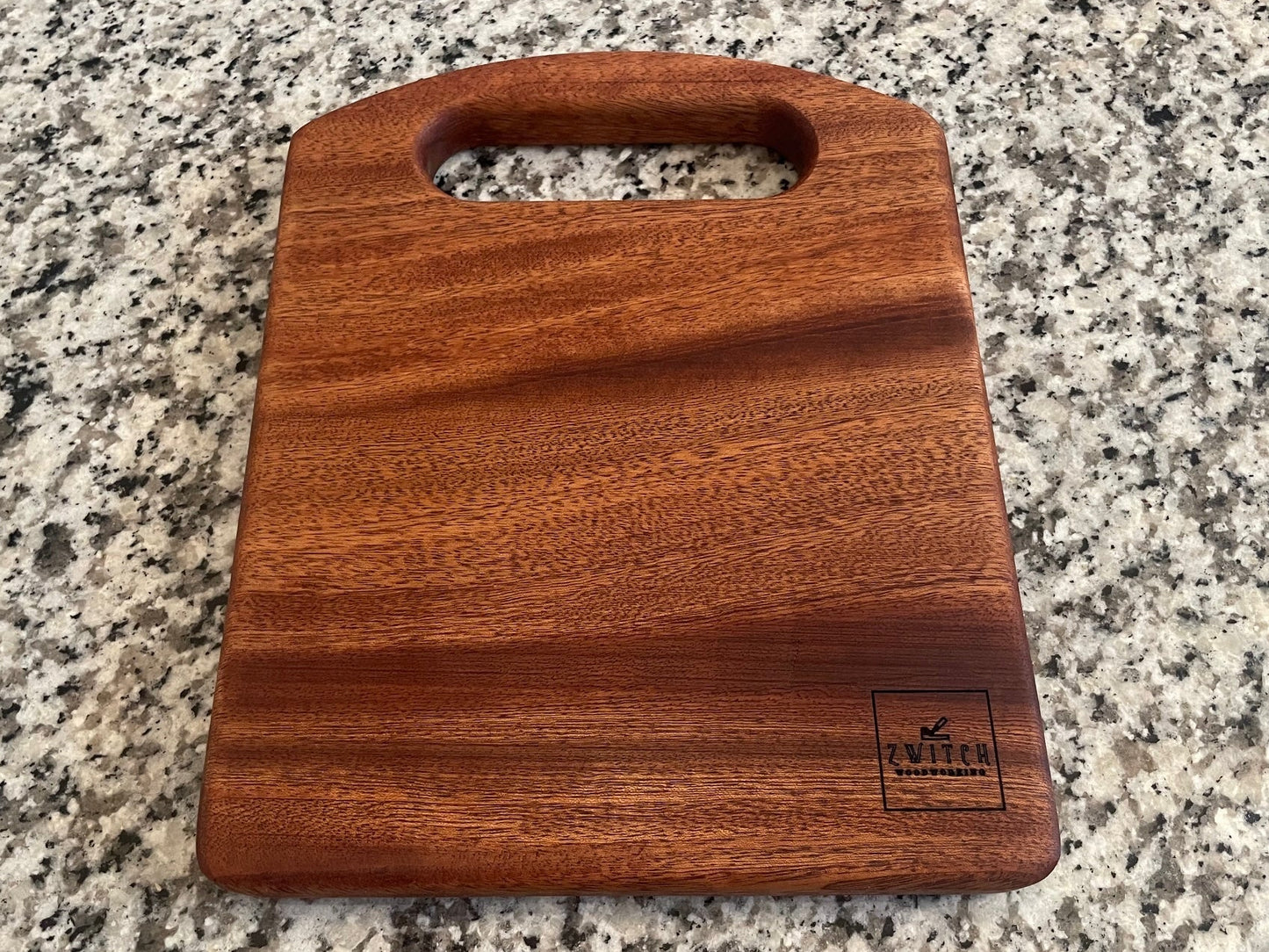Wooden cutting board with a handle on a granite countertop